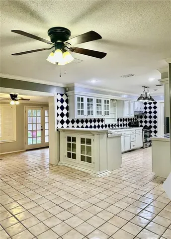 a open kitchen with white cabinets a stove and a window