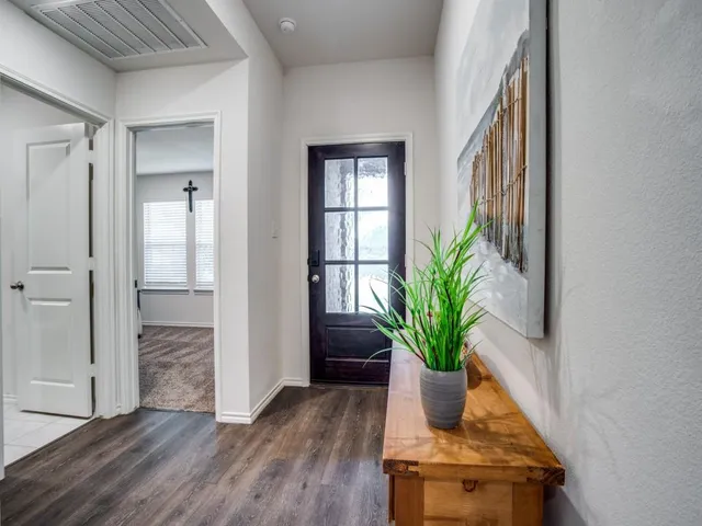 a view of a hallway with wooden floor and a potted plant
