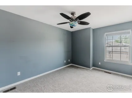 an empty room with a window and ceiling fan