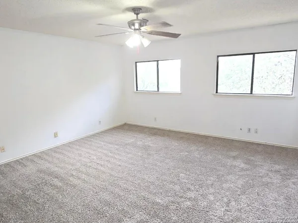 an empty room with a window and a fan