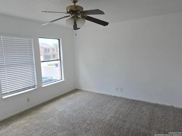 an empty room with a window and a ceiling fan