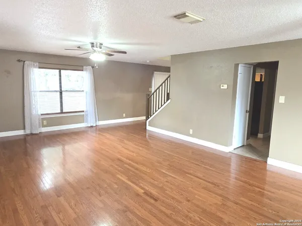 a view of an empty room with window and wooden floor