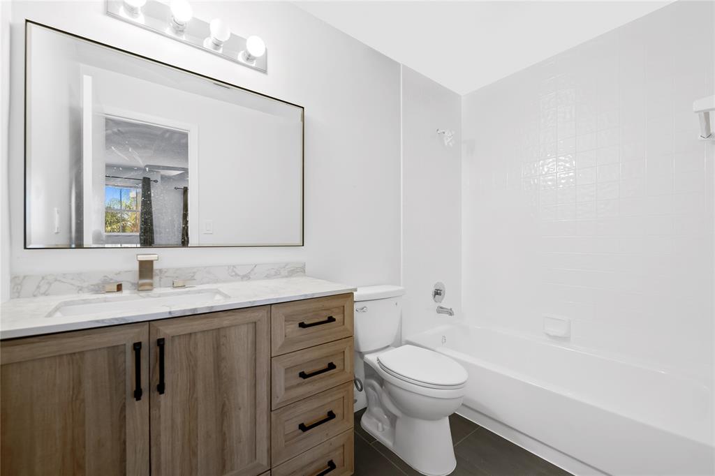 8245 Northwest 70th Street Tamarac, FL 33321 - Photo 12 of 29 a bathroom with a toilet a sink a tub and mirror