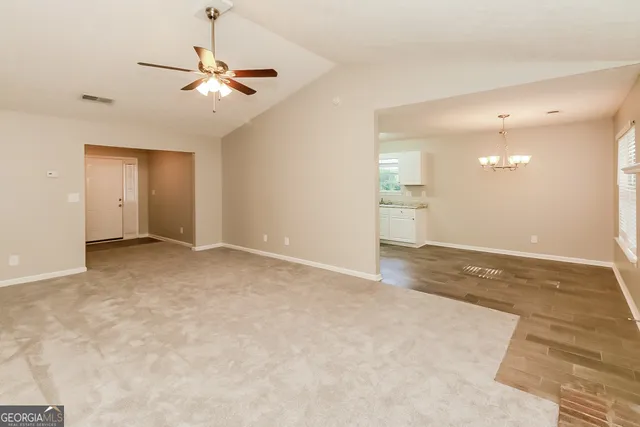a view of an empty room with a chandelier fan