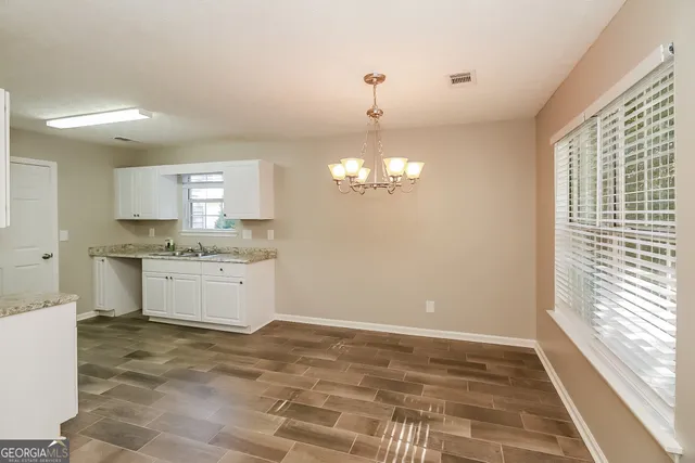 a view of a kitchen with a sink dishwasher a stove and white cabinets with wooden floor