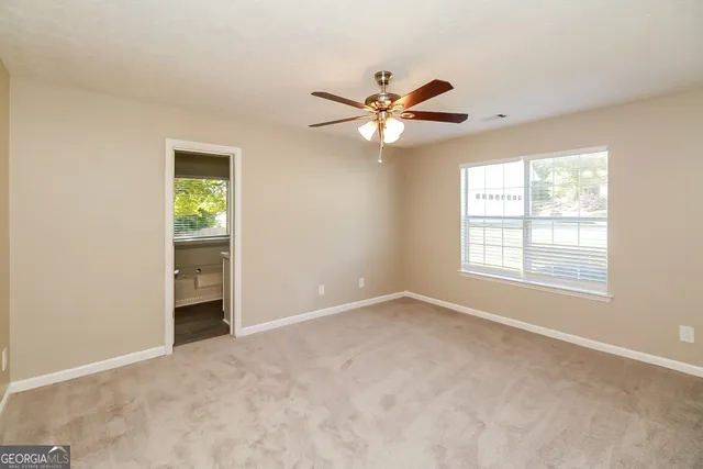 an empty room with windows and fan