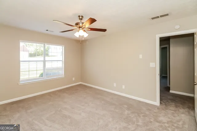 an empty room with windows and fan