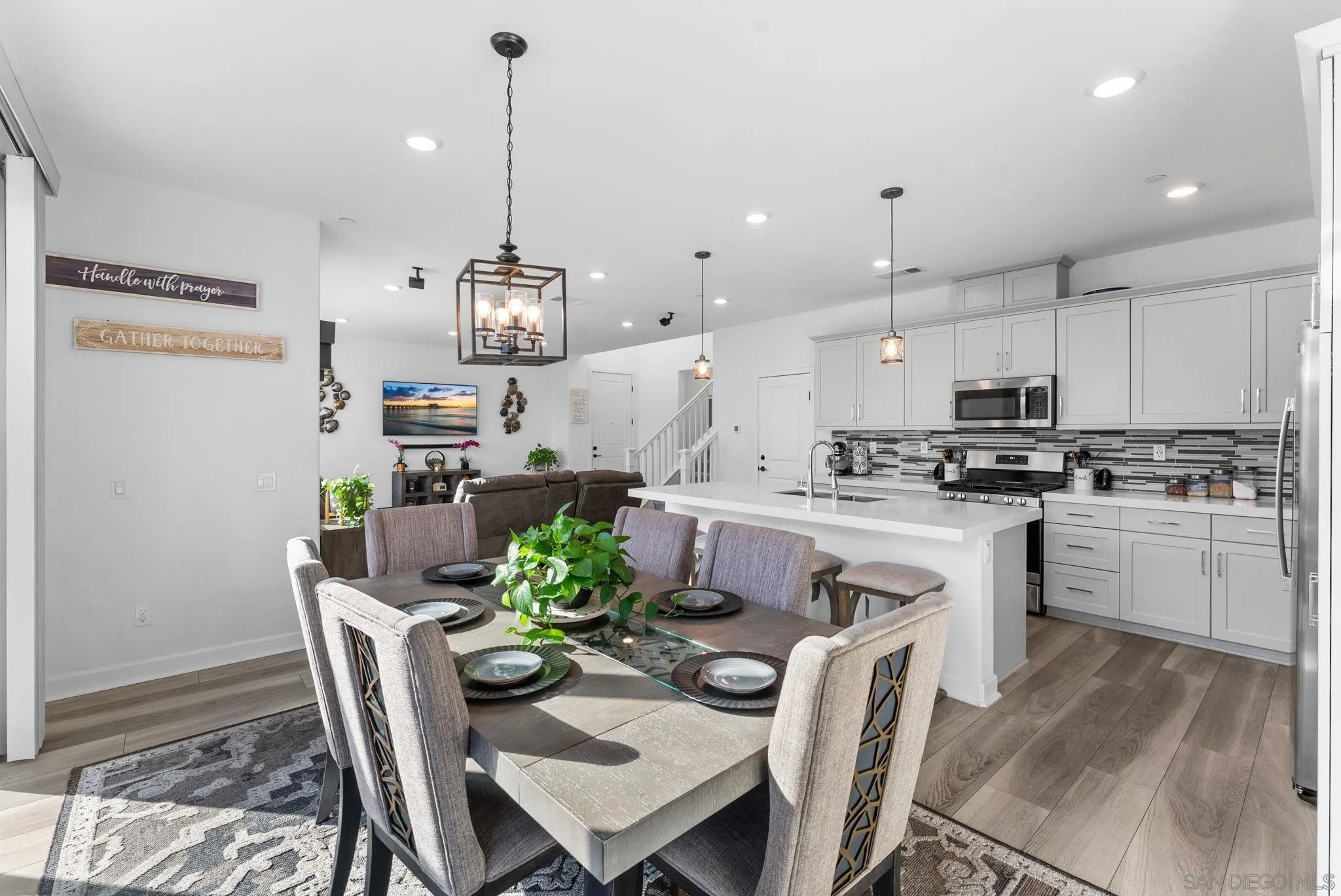 10129 Hercules Way Spring Valley, CA 91977 - Photo 12 of 52 a kitchen with stainless steel appliances granite countertop a refrigerator a sink dishwasher a dining table and chairs with wooden floor