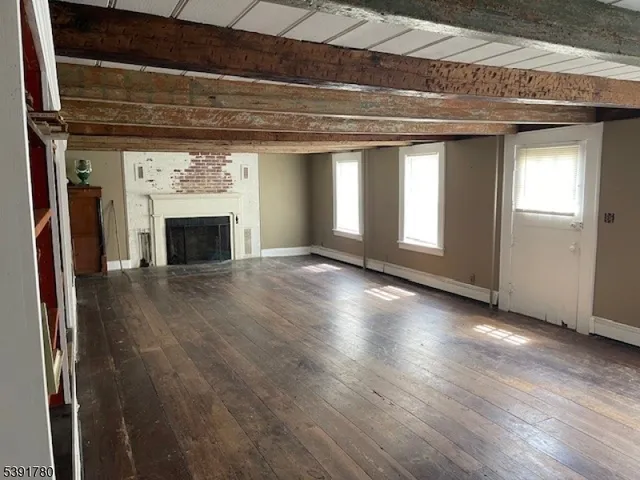 a view of an empty room with wooden floor fireplace and a window
