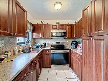 a kitchen with kitchen island granite countertop a sink dishwasher stove and cabinets with wooden floor
