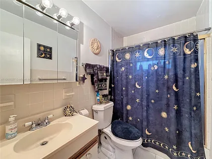 a bathroom with a sink a toilet and shower curtain