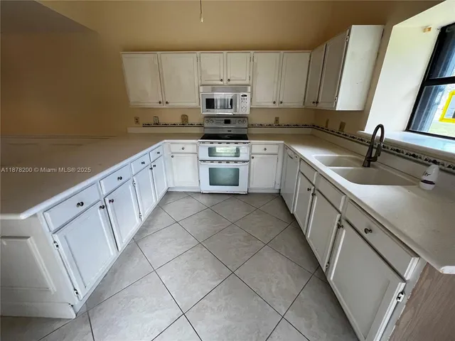 a kitchen with granite countertop white cabinets and white appliances
