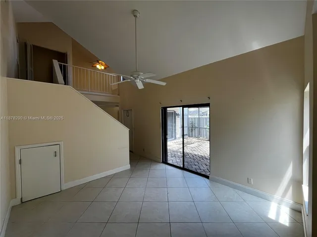 a view of an empty room with window and chandelier fan