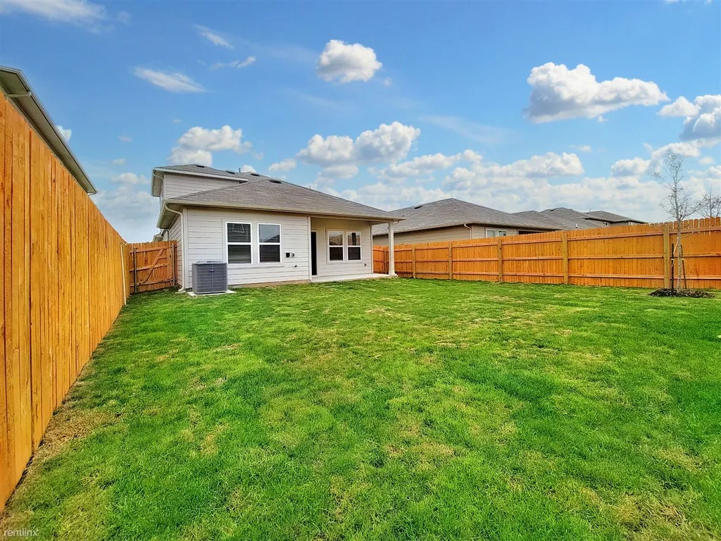 419 Sickle Loop Kyle, TX 78640 - Photo 34 of 35 A fenced green lawn offers a perfect private outdoor space for leisure and activity.