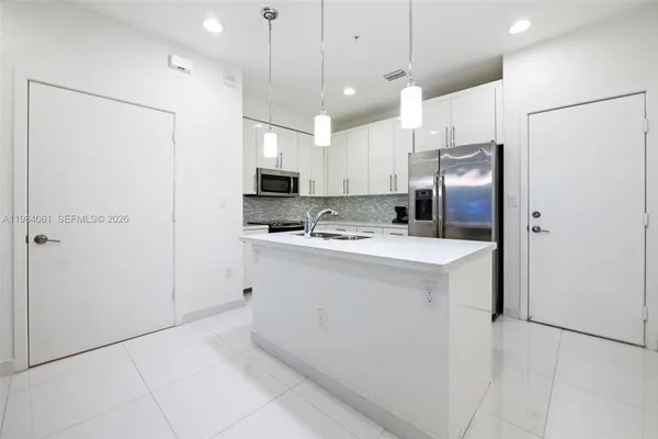 a kitchen with kitchen island a refrigerator and a sink