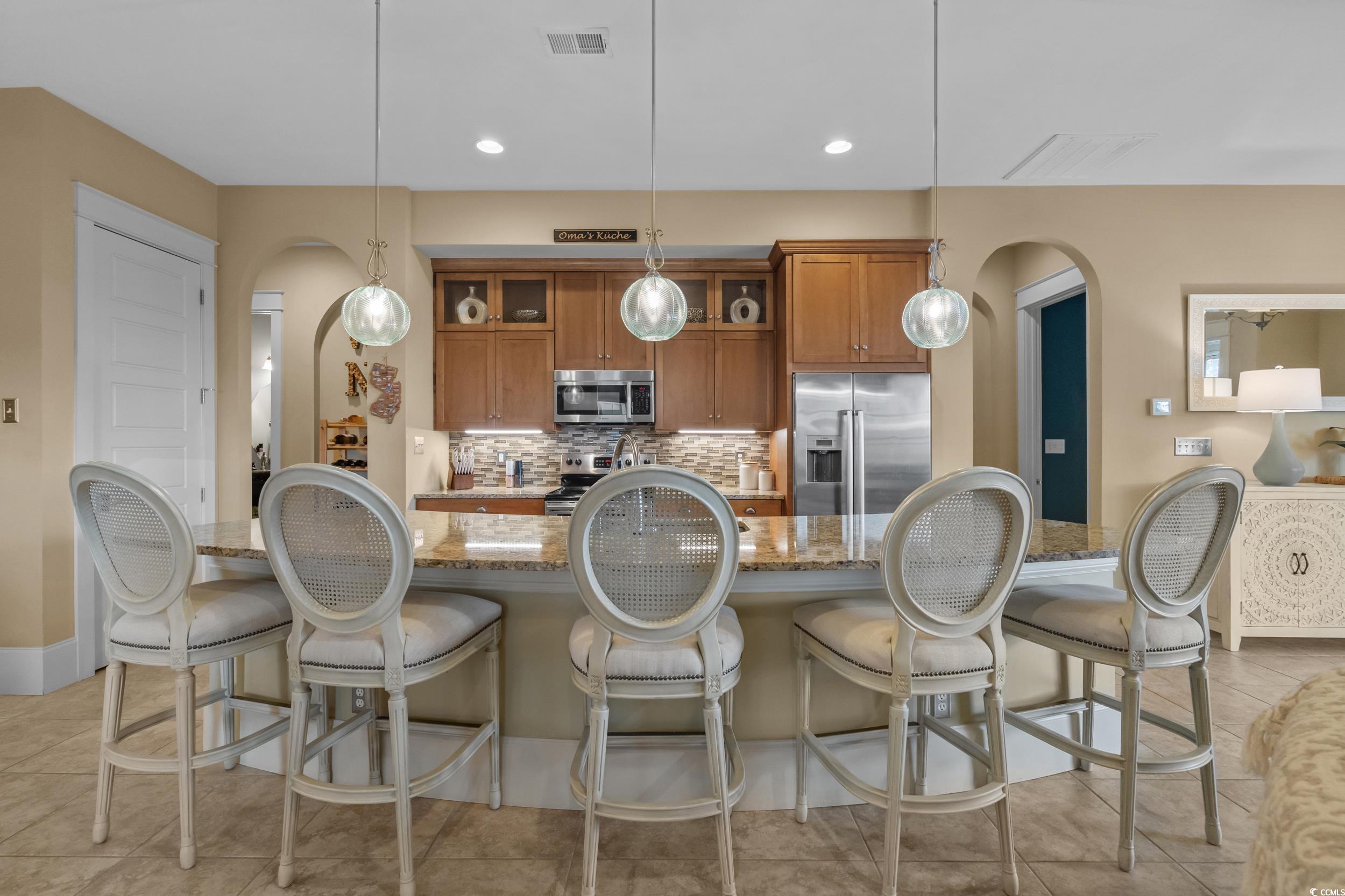 2604 Painted Trillium Court Myrtle Beach, SC 29579 - Photo 8 of 40 Kitchen with arched walkways, brown cabinets, decorative light fixtures, appliances with stainless steel finishes, and recessed lighting