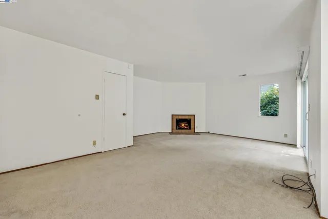 an empty room with windows and fireplace
