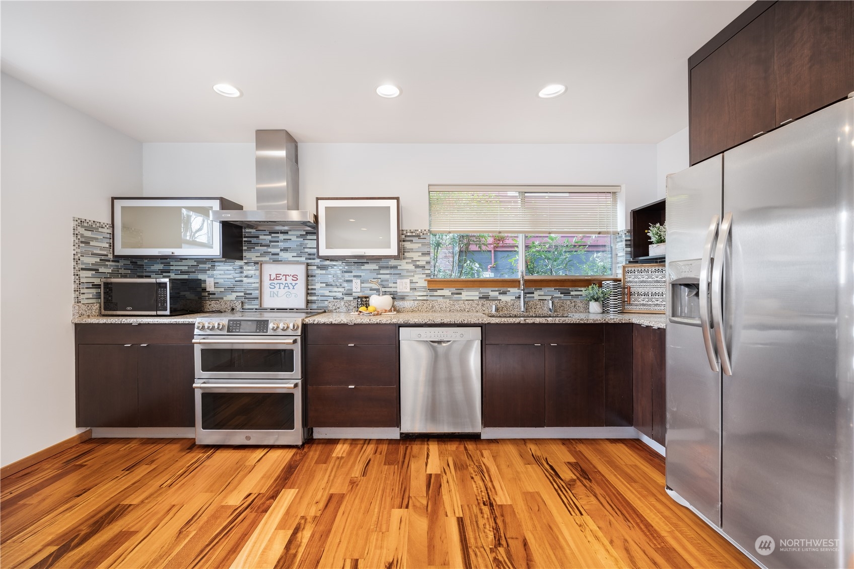 562 Galer Street, Unit A Seattle, WA 98109 - Photo 11 of 30 a kitchen with stainless steel appliances kitchen island granite countertop a refrigerator stove and oven