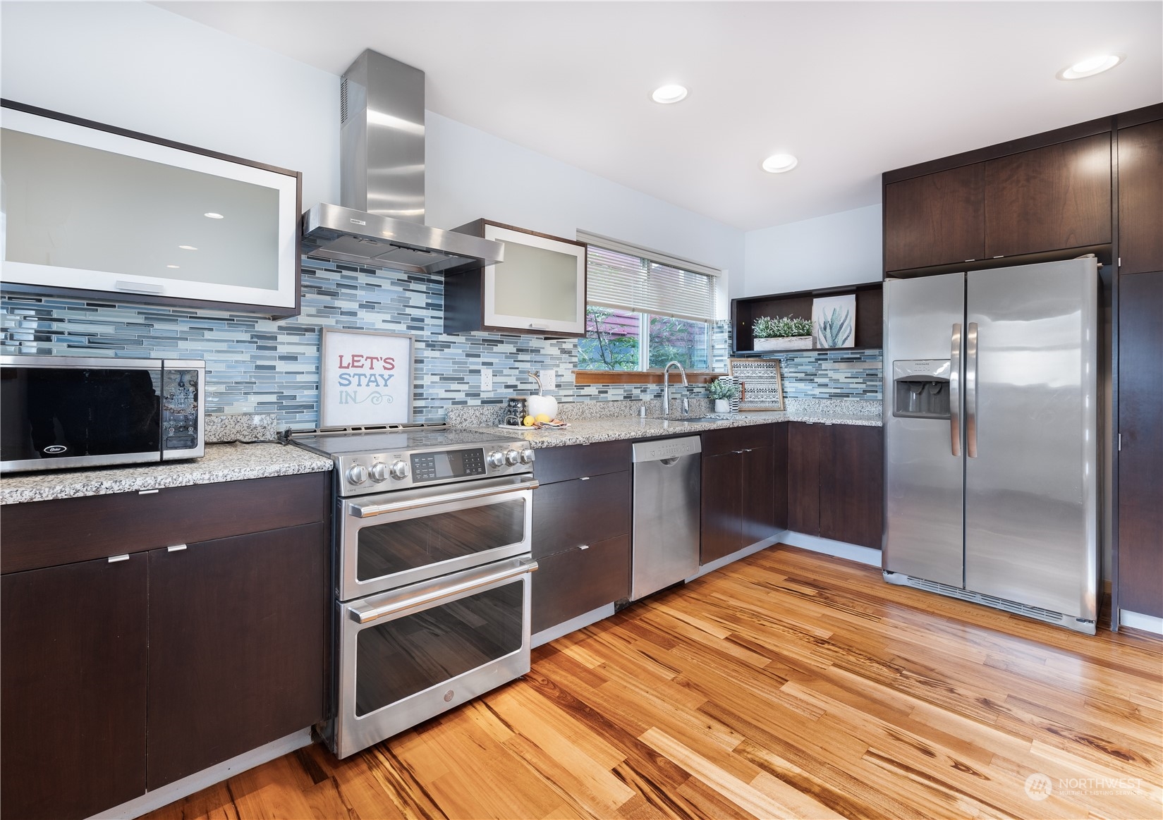 562 Galer Street, Unit A Seattle, WA 98109 - Photo 10 of 30 a kitchen with stainless steel appliances kitchen island granite countertop a refrigerator and a stove top oven