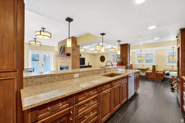 714 Draper Heights Way Draper, UT 84020 - Photo 53 of 88 Kitchen with wood finish cabinetry, light stone counters, hanging light fixtures, a fireplace, and a textured ceiling