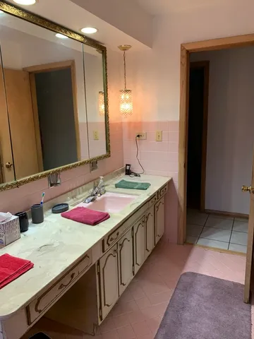 a bathroom with a granite countertop double vanity and a large mirror