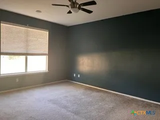 an empty room with a window and a ceiling fan