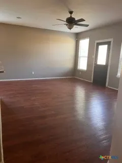 a view of an empty room with window and wooden floor