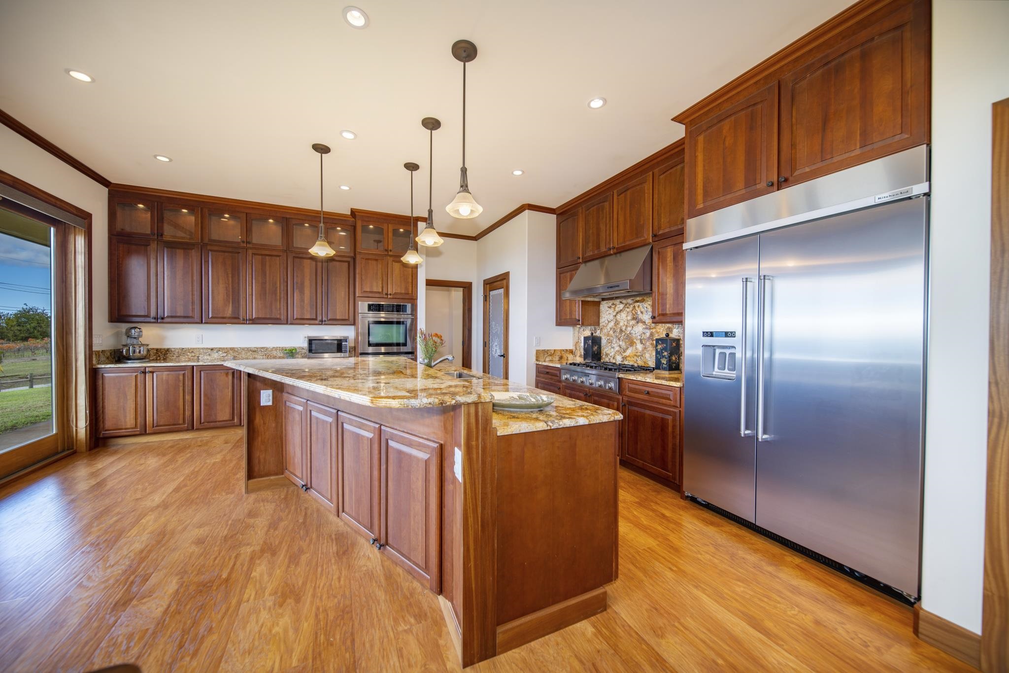 a large kitchen with stainless steel appliances kitchen island granite countertop a large kitchen island and a wooden floors