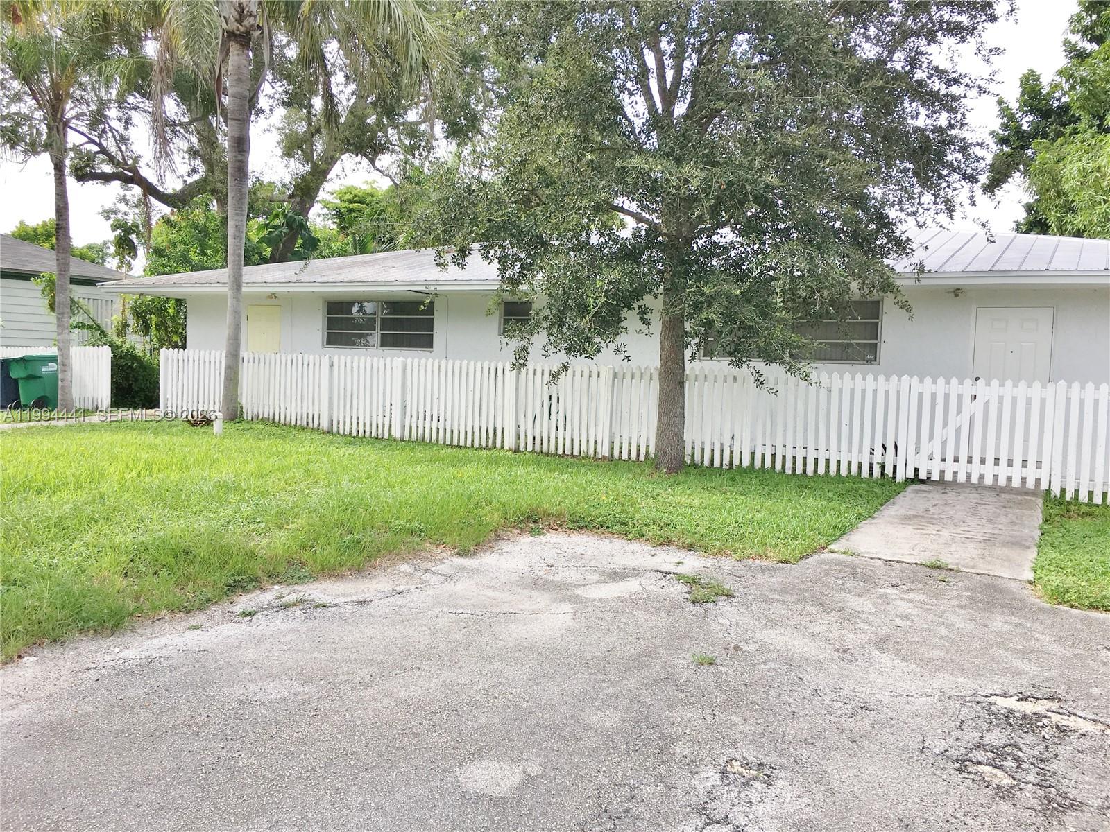 a view of a house with a yard and a large tree