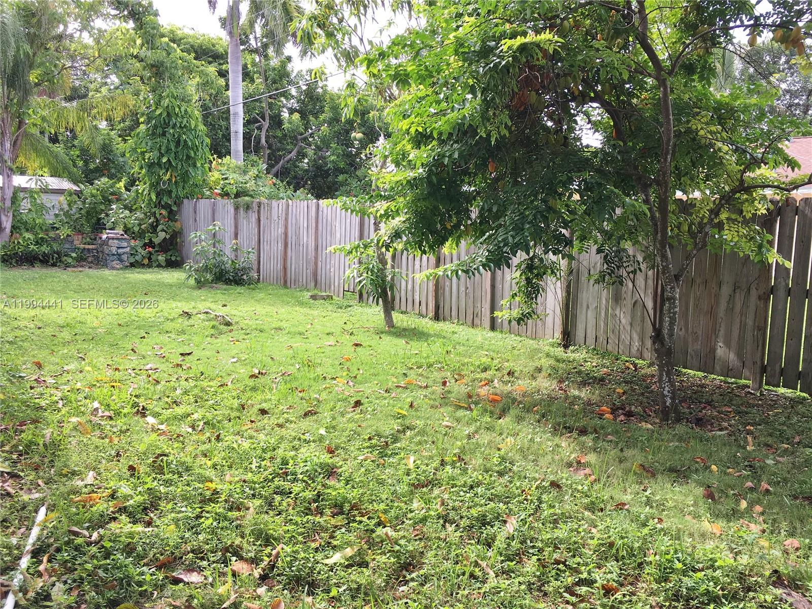 5831 Southwest 62nd Street, Unit WEST Miami, FL 33143 - Photo 15 of 16 a view of a backyard with large trees and wooden fence