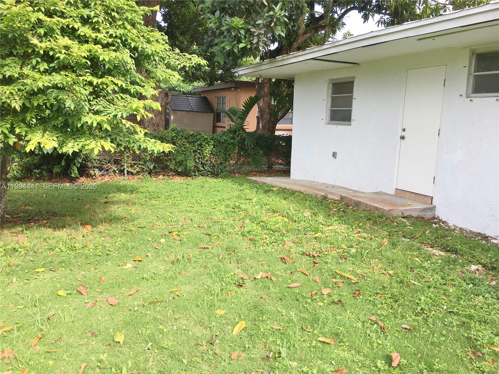 5831 Southwest 62nd Street, Unit WEST Miami, FL 33143 - Photo 16 of 16 a backyard of a house with plants and large tree