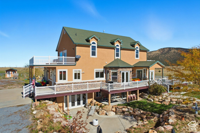 4768 East Hickman Canyon Road Stockton, UT 84071 - Photo 60 of 85 Elevated view of south side of home with french doors, stucco siding, a patio, and a deck.