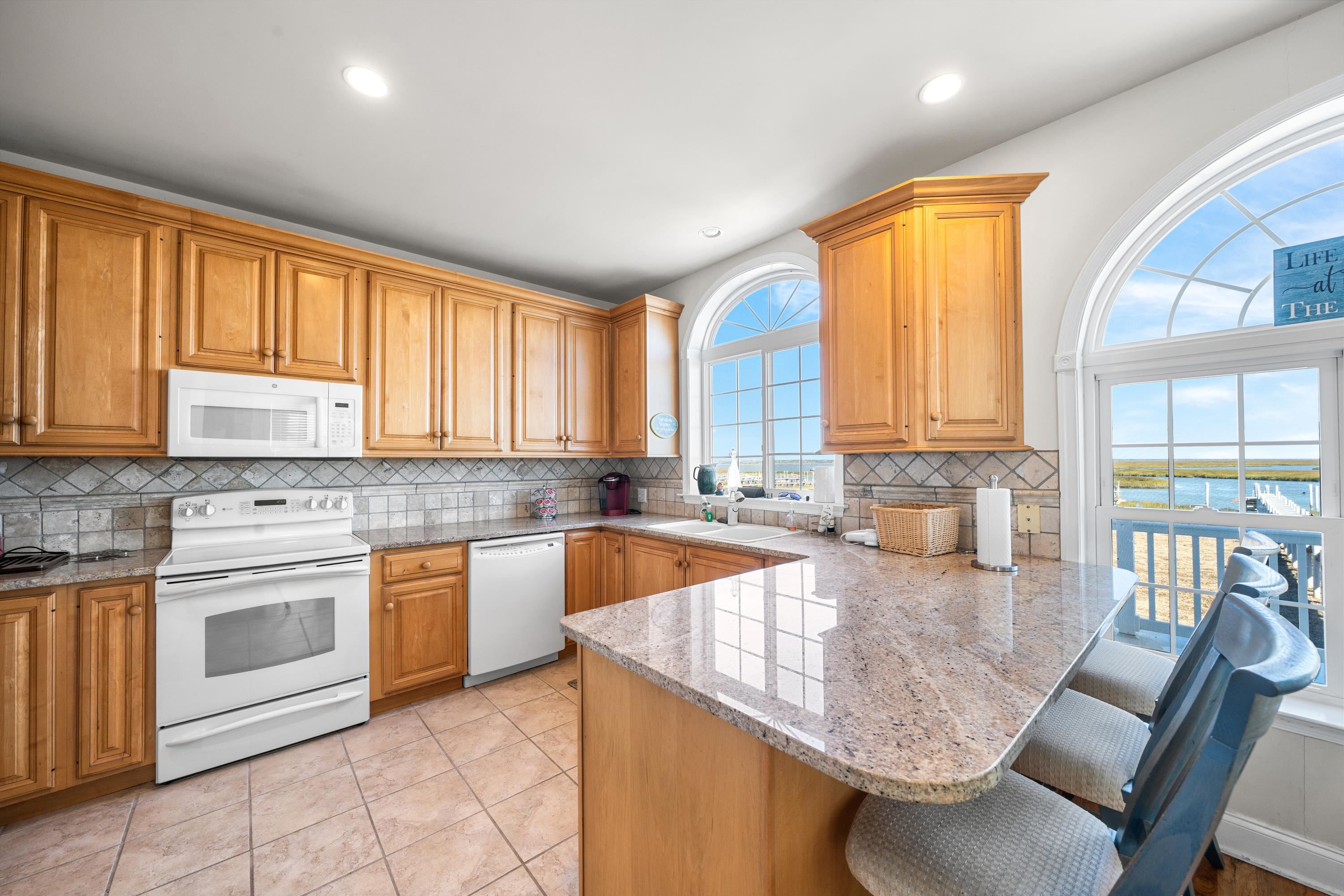 448 Avalon Avalon, NJ 08202 - Photo 3 of 32 a kitchen with stainless steel appliances granite countertop a stove a sink a microwave dining table and chairs