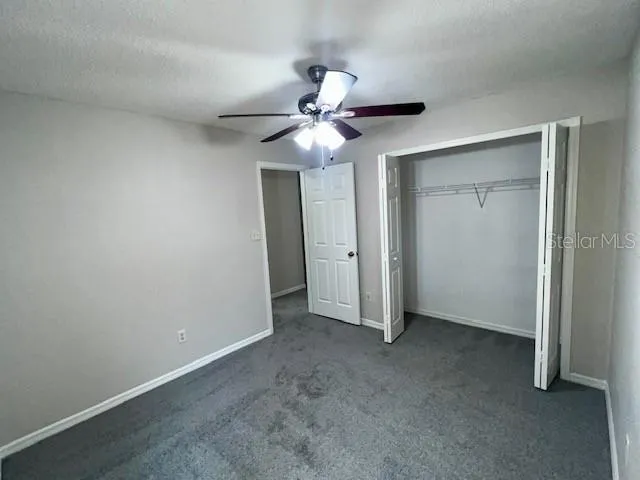 an empty room with windows and fan