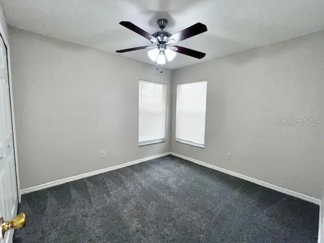 an empty room with closet and a ceiling fan