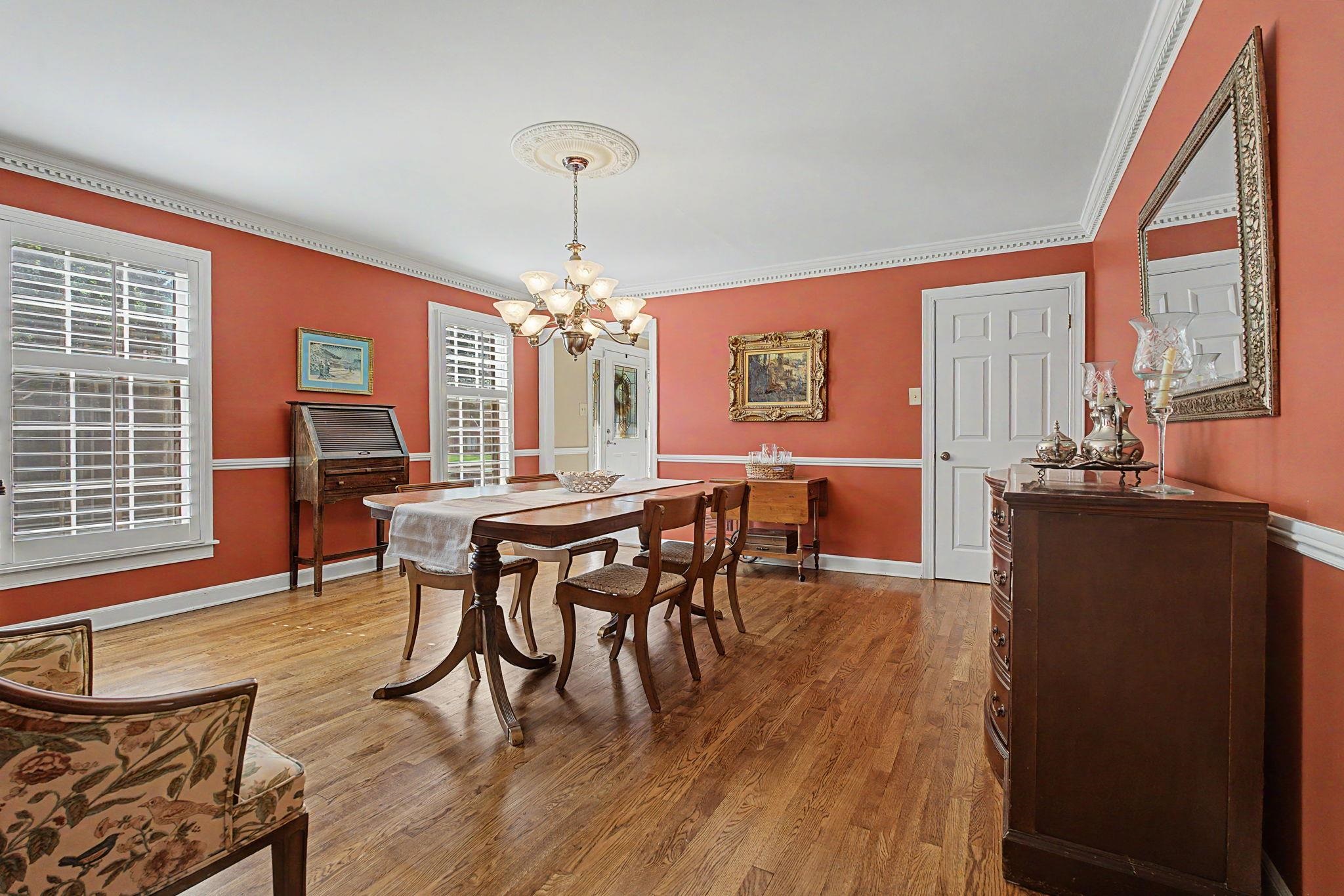 1929 Miller Farms Road Germantown, TN 38138 - Photo 12 of 40 Warm-toned room featuring wood-finish flooring, two large windows with plantation shutters, a decorative chandelier, crown molding, and wainscoting