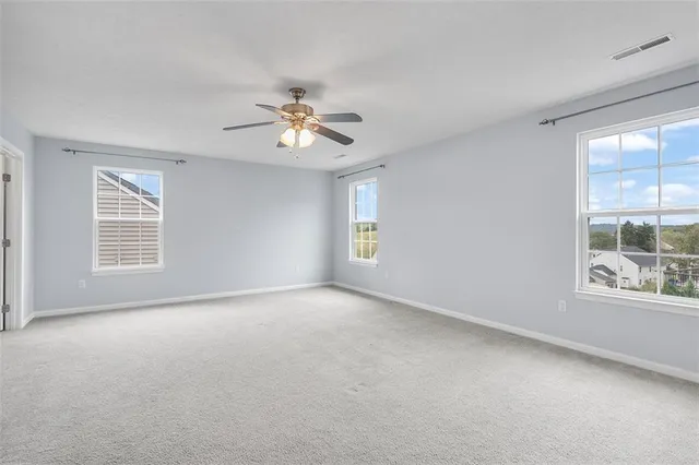 an empty room with windows and ceiling fan