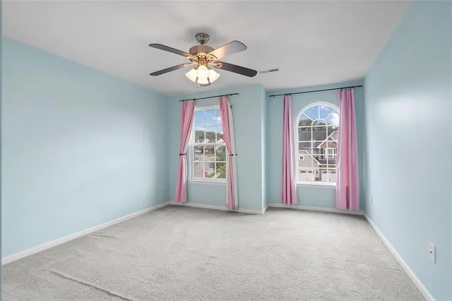 an empty room with windows and chandelier fan