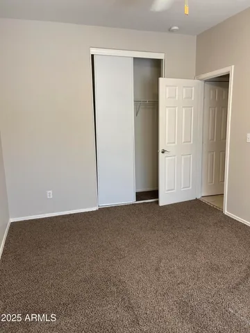 an empty room with a chandelier fan and windows