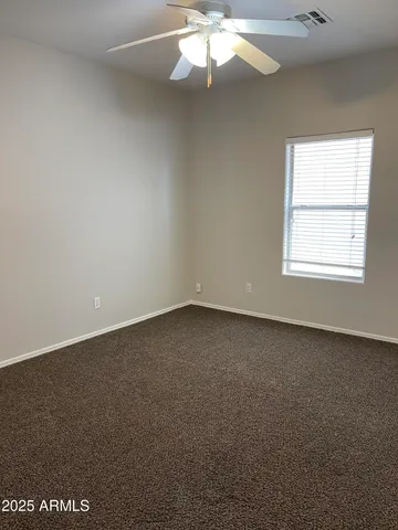 an empty room with a chandelier fan and windows
