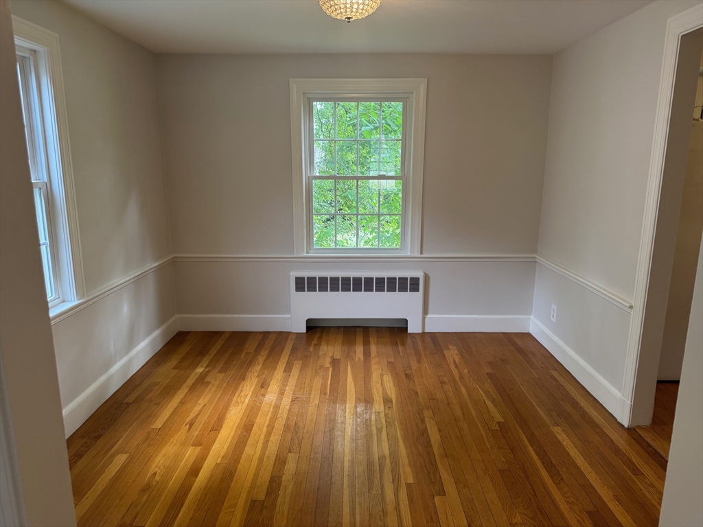161 Hunnewell Street, Unit 1 Needham, MA 02494 - Photo 5 of 13 a view of an empty room with wooden floor and a window
