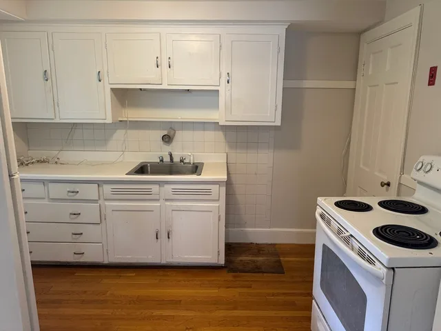 a kitchen with white cabinets and appliances