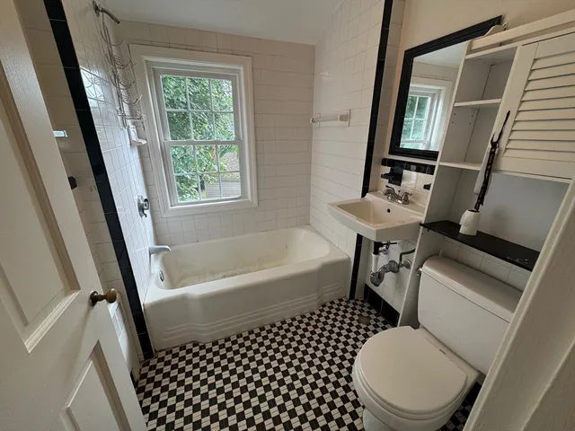 a bathroom with a sink a toilet a mirror a tub and shower