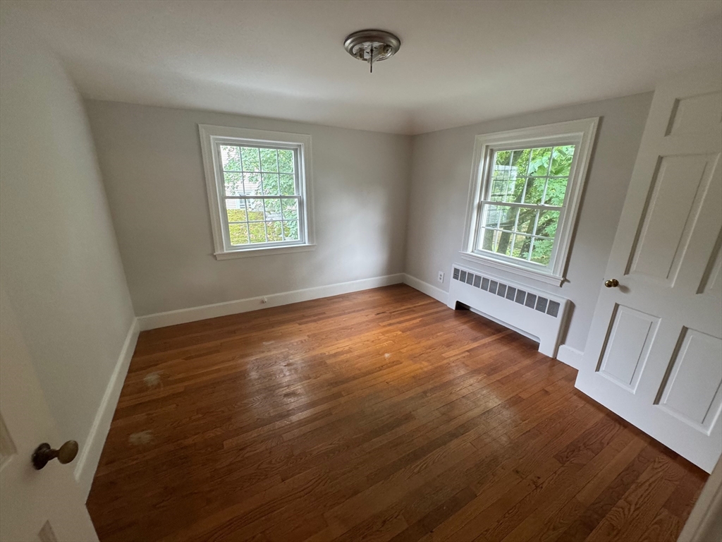 161 Hunnewell Street, Unit 1 Needham, MA 02494 - Photo 10 of 13 a view of an empty room with a window and wooden floor