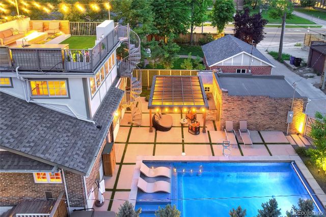 a view of a brick house with a small yard and a large tree
