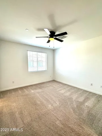 an empty room with windows and ceiling fan