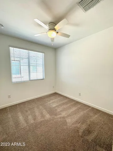 an empty room with windows and fan