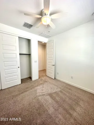 an empty room with a ceiling fan and closet