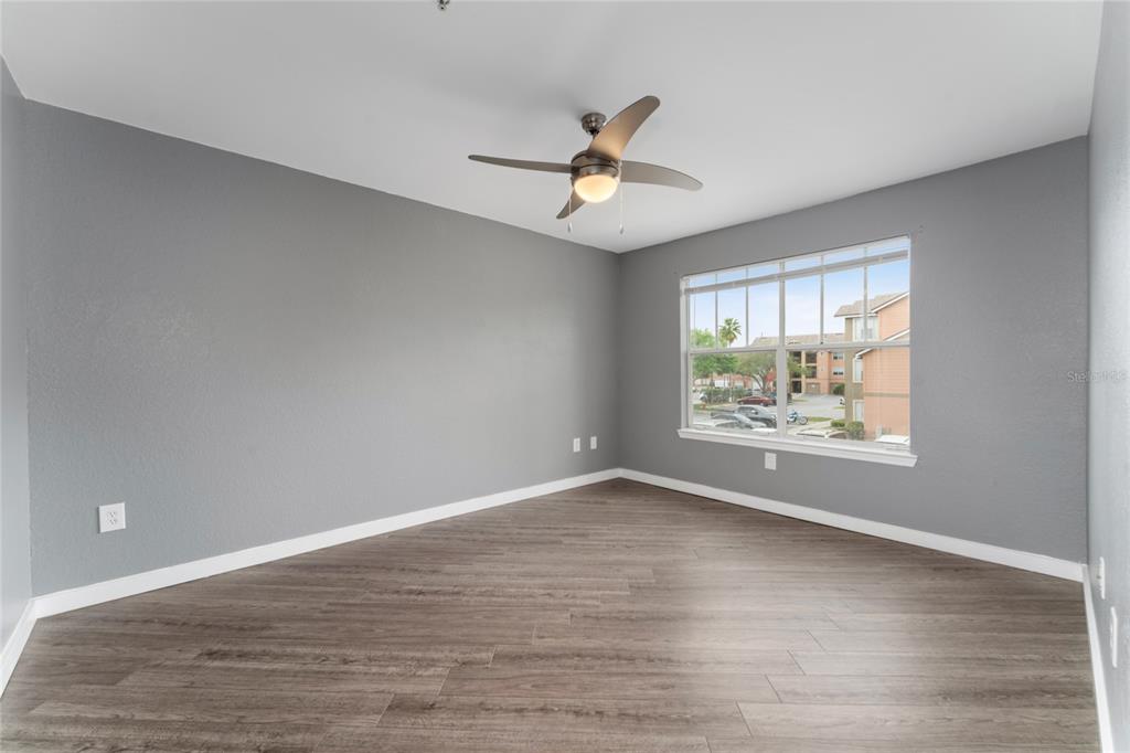2203 Key W Court, Unit 422 Kissimmee, FL 34741 - Photo 14 of 41 an empty room with wooden floor fan and windows