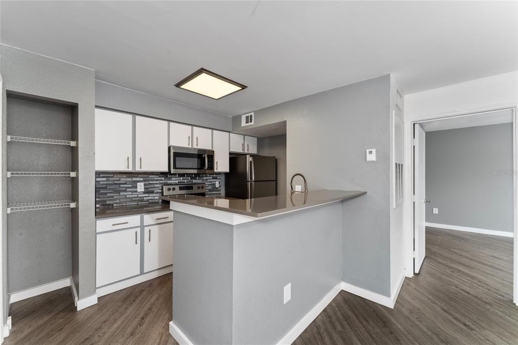 2203 Key W Court, Unit 422 Kissimmee, FL 34741 - Photo 7 of 41 a kitchen with stainless steel appliances a sink a stove a refrigerator cabinets and a wooden floor